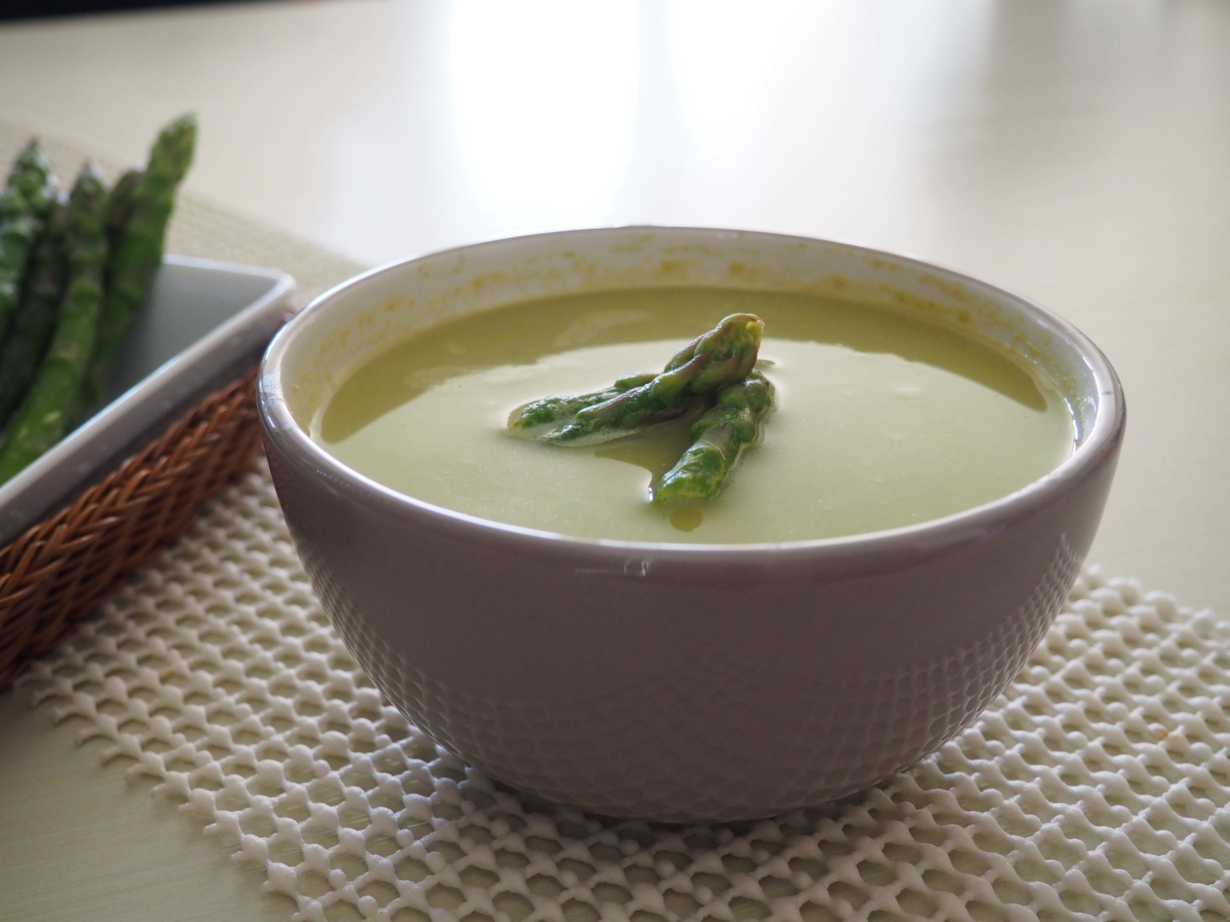 A bowl of creamed asparagus, sweet potato and fennel soup, with asparagus spears on top as a decoration.