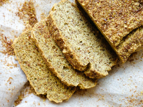 A loaf of flaxseed Paleo bread sliced up on a cloth. Birds eye view.