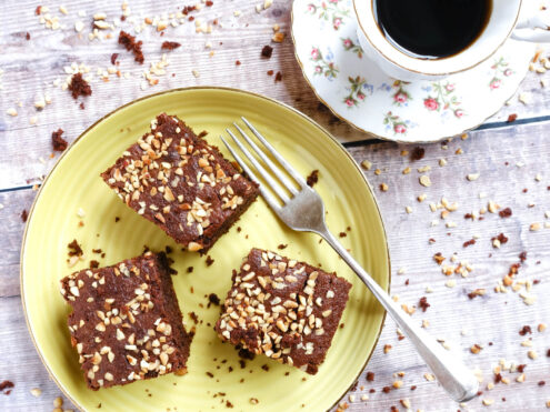 A plate of cake, with a fork and cup of black coffee.