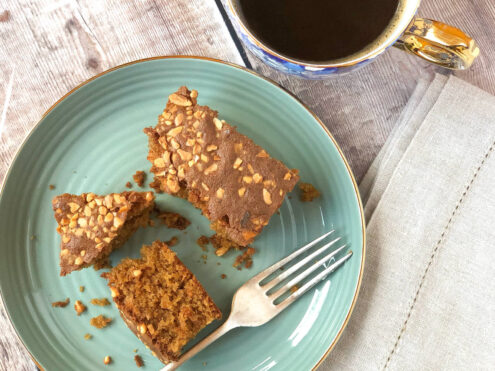 A plate of cake with a fork, and a cup of black coffee.
