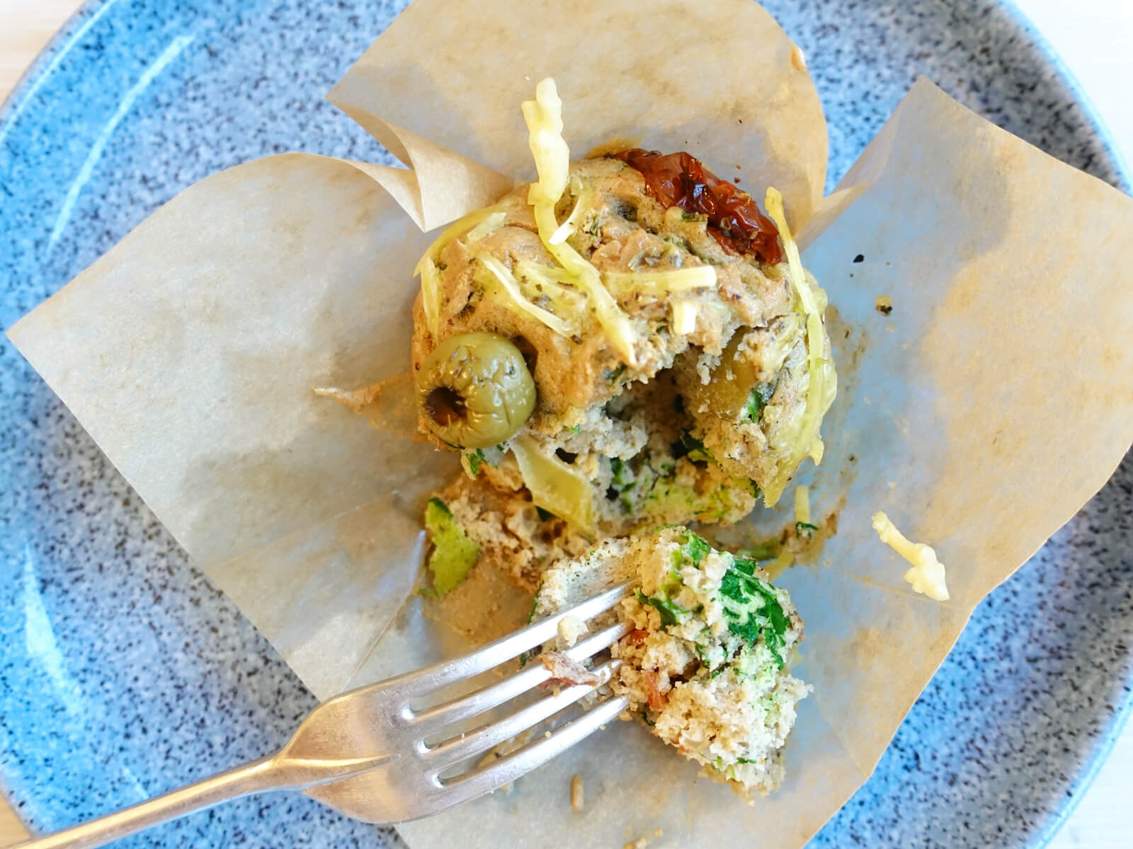 Spinach and Tomato Paleo Muffins made with spinach and tomatoes, individually wrapped, shown here on a plate with a fork. Another delicious mental health recipe from the Inflammation Pioneer.