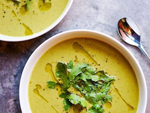 Two bowls of creamy green soup with parsley on top and a drizzle of oil
