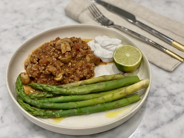 A bowl of turkey chili with asparagus and coconut yogurt.