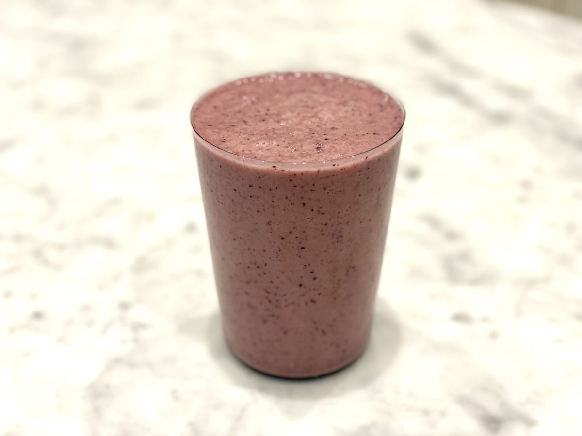 A glass of strawberry and blueberry smoothie that contains other skin loving ingredients.