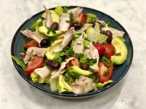 A colourful bowl of salad with chicken, avocado and wonderfully red tomatoes.