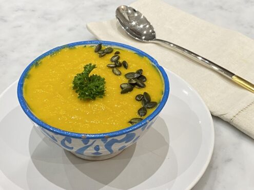 Carrot soup made with coconut and topped with parsley and seeds, showcasing the recipe from a gut-friendly lifestyle plan.