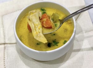 A bowl of Greek chicken soup with inflammation reducing turmeric, which has given it a wonderful golden colour. A healing soup.