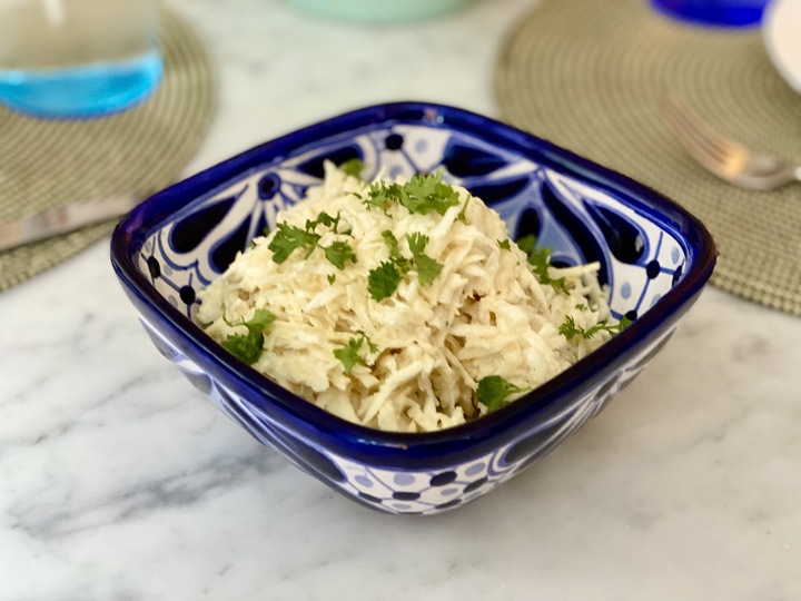 A bowl of creamy looking grated celeriac salad with green parsley on top: a recipe for reducing inflammation in the body.