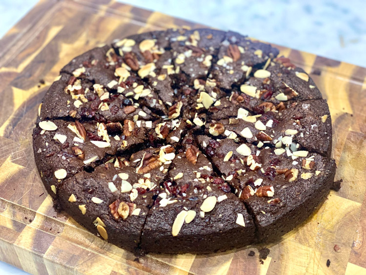 A Brownies Cake cut into eight segments, decorated with nuts and cranberries, showcasing a gut-friendly holiday cake recipe.