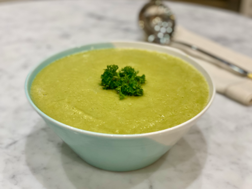 A bowl of vibrant green soup for digestive health, comprising of zucchinis (courgettes) and leeks.