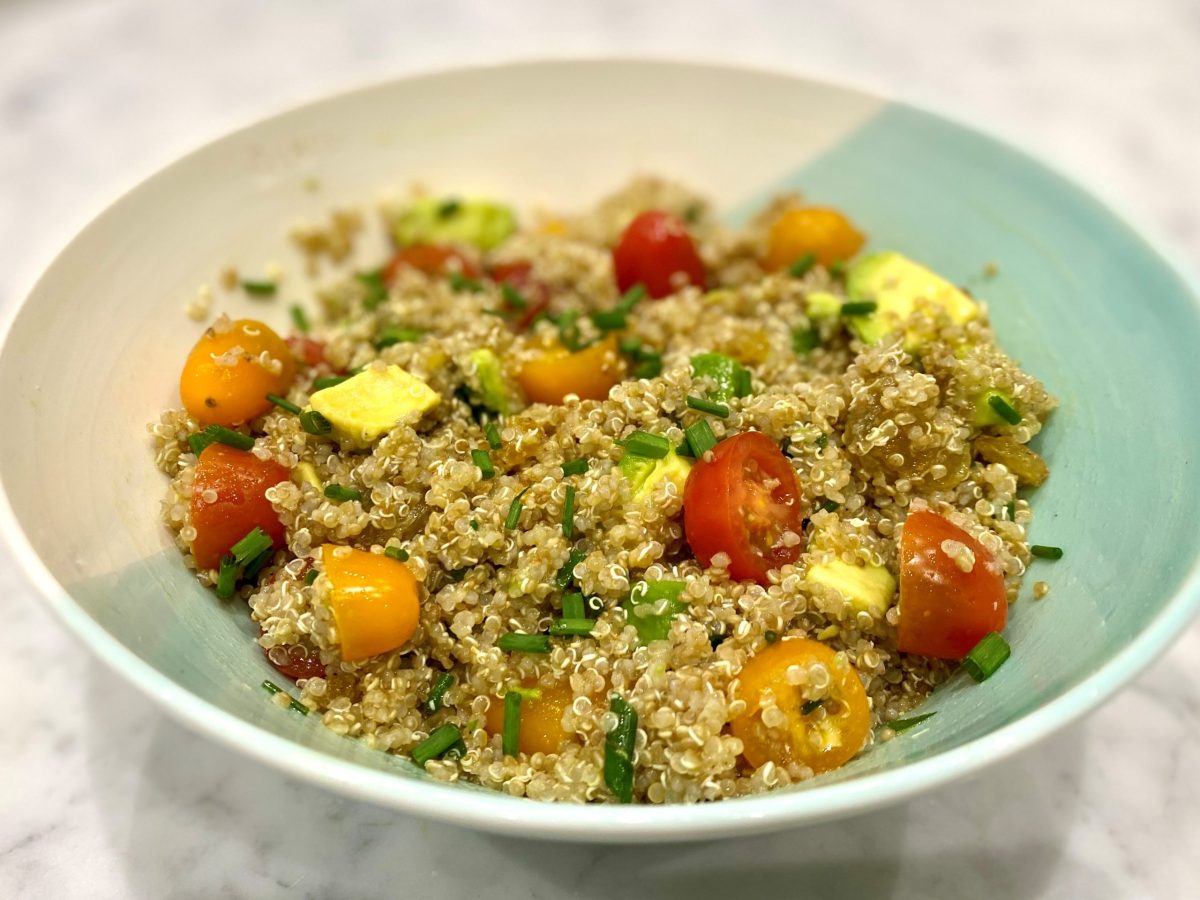 A bowl of quinoa salad with tomatoes and avocado
