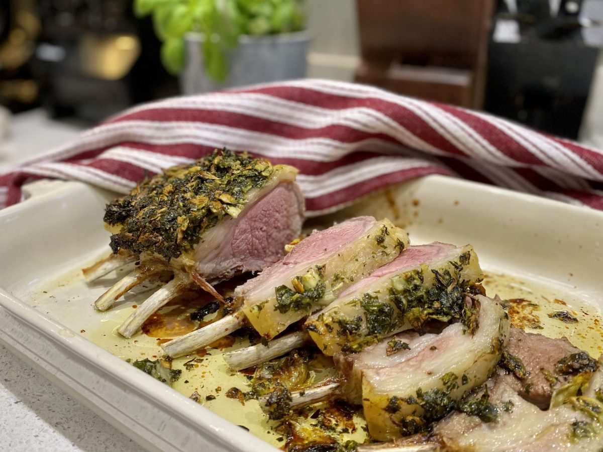A rack of lamb in a dish with herbs on top.