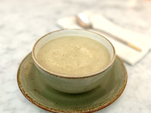 A green bowl full of white soup on a saucer