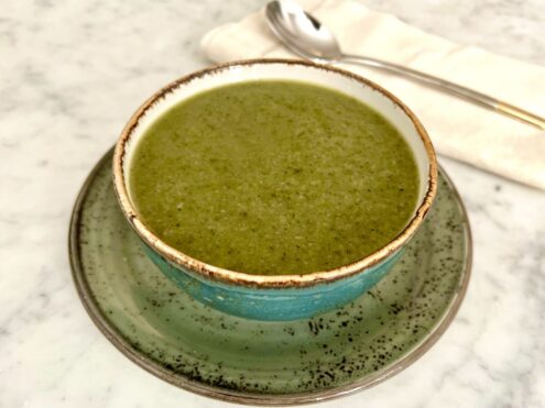 A bowl of green soup on a saucer