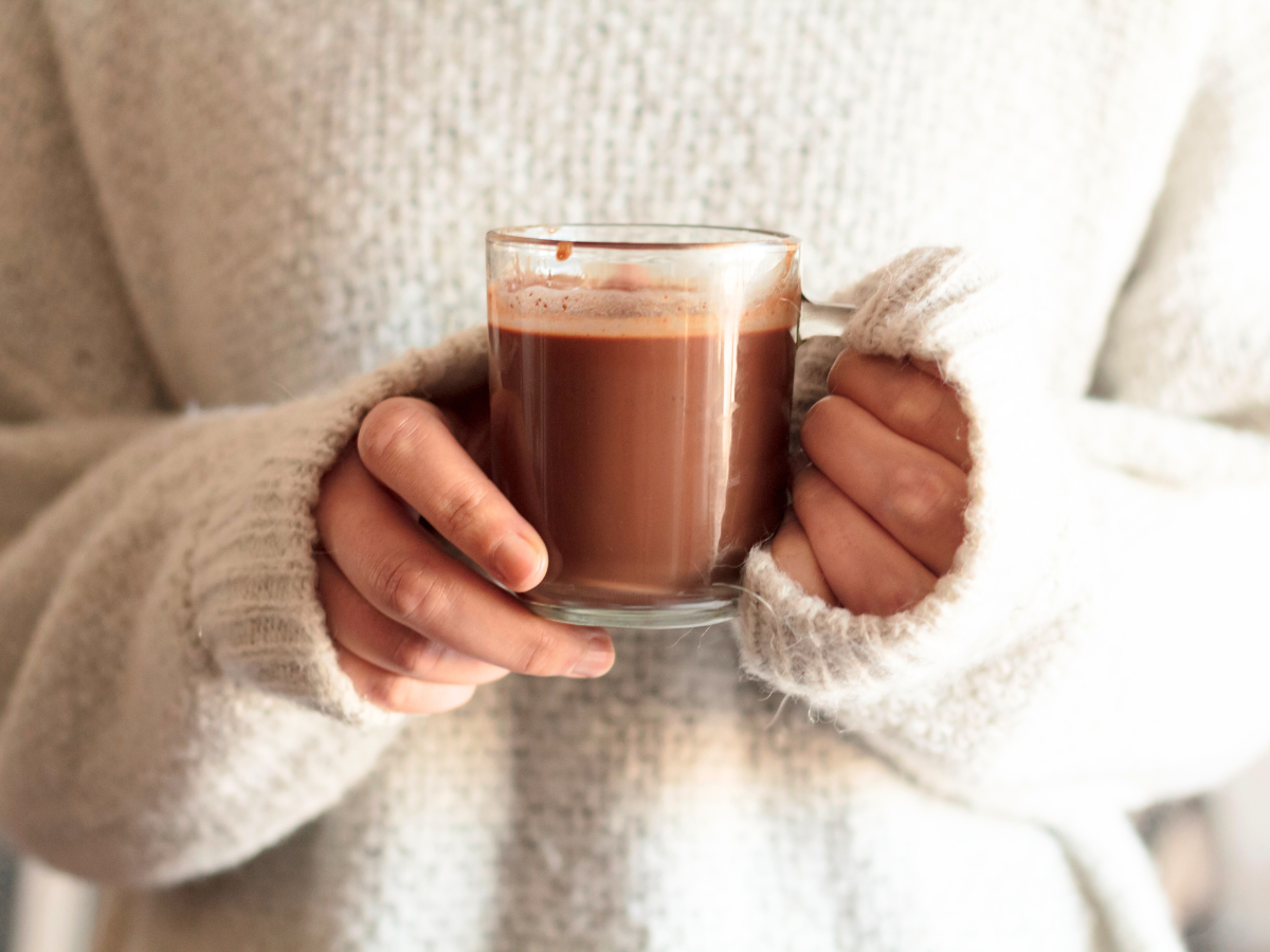 close up of hands holding a glass mug of Hot Chocolate