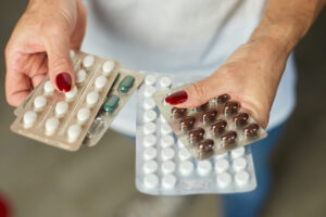 A female holding four blister packs of medication.