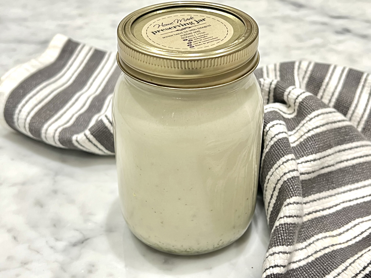 A bottle of home-made chives dressing and a black and white striped tea towel at the side.