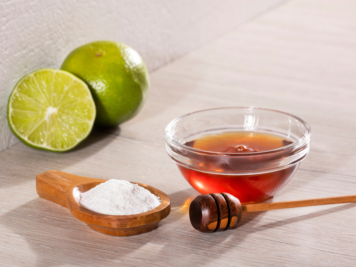 A bowl of honey, with a bowl of white powder and a halved lime.