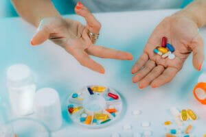 Tablets, pills, medication, medicine on a table, in a bowl and in hands.