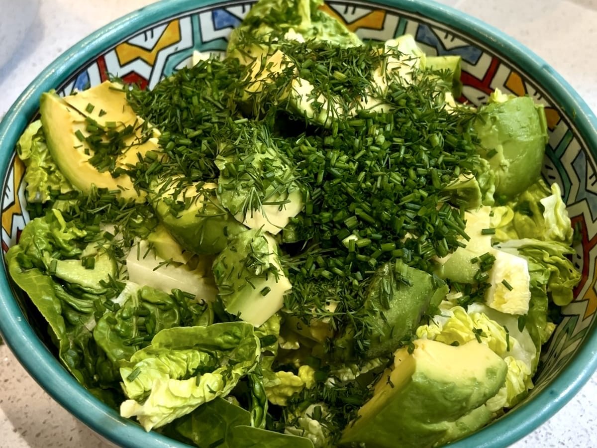 bowl of avocado and lettuce salad garnished with dill and chives