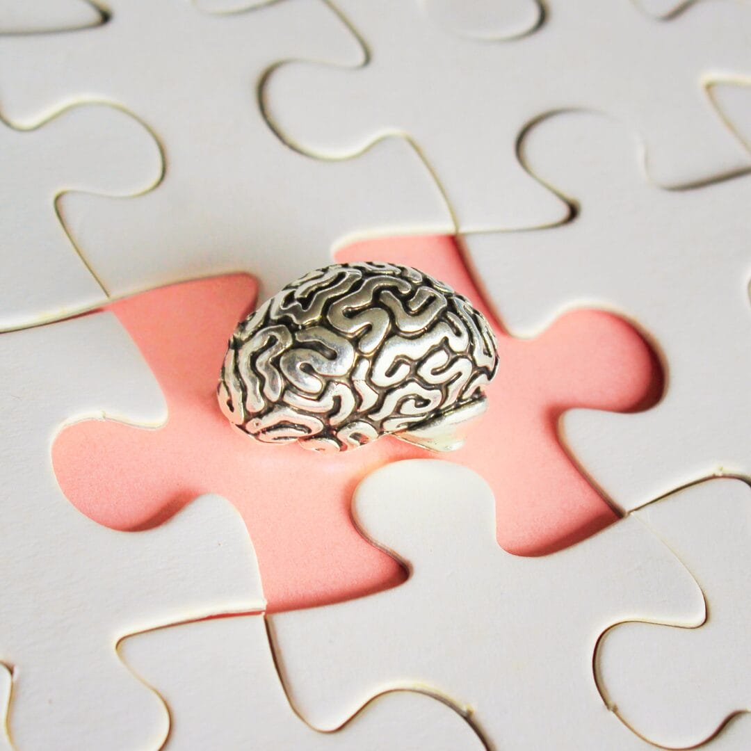 silver brain figurine resting on a jigsaw puzzle