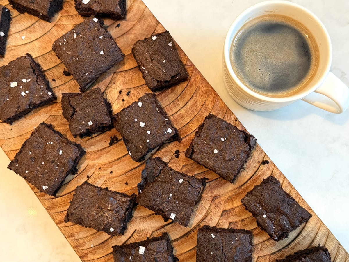 Chocolate and Espresso Brownies on a wooden serving board alongside a mug of coffee. Yummy anti inflammatory brownies.