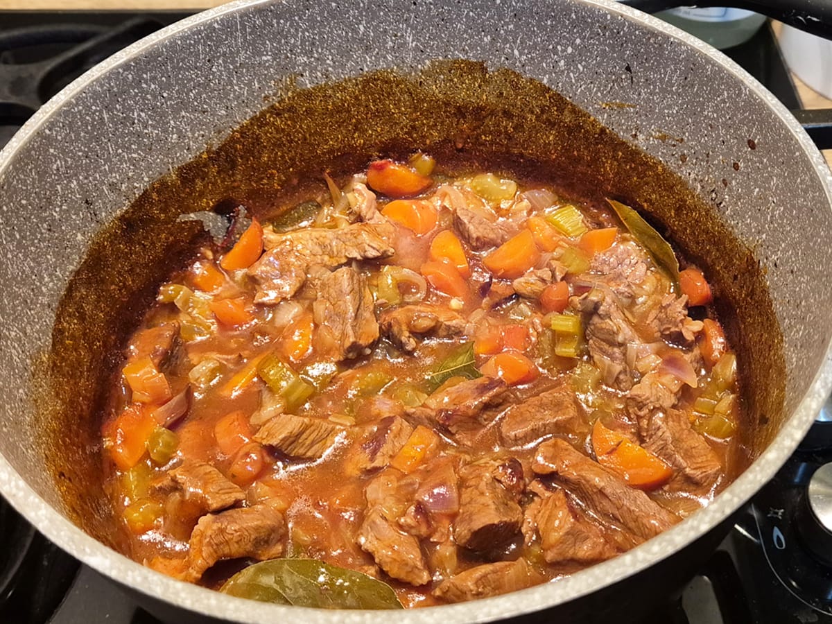 casserole dish with beef steak, carrots, celery and onions